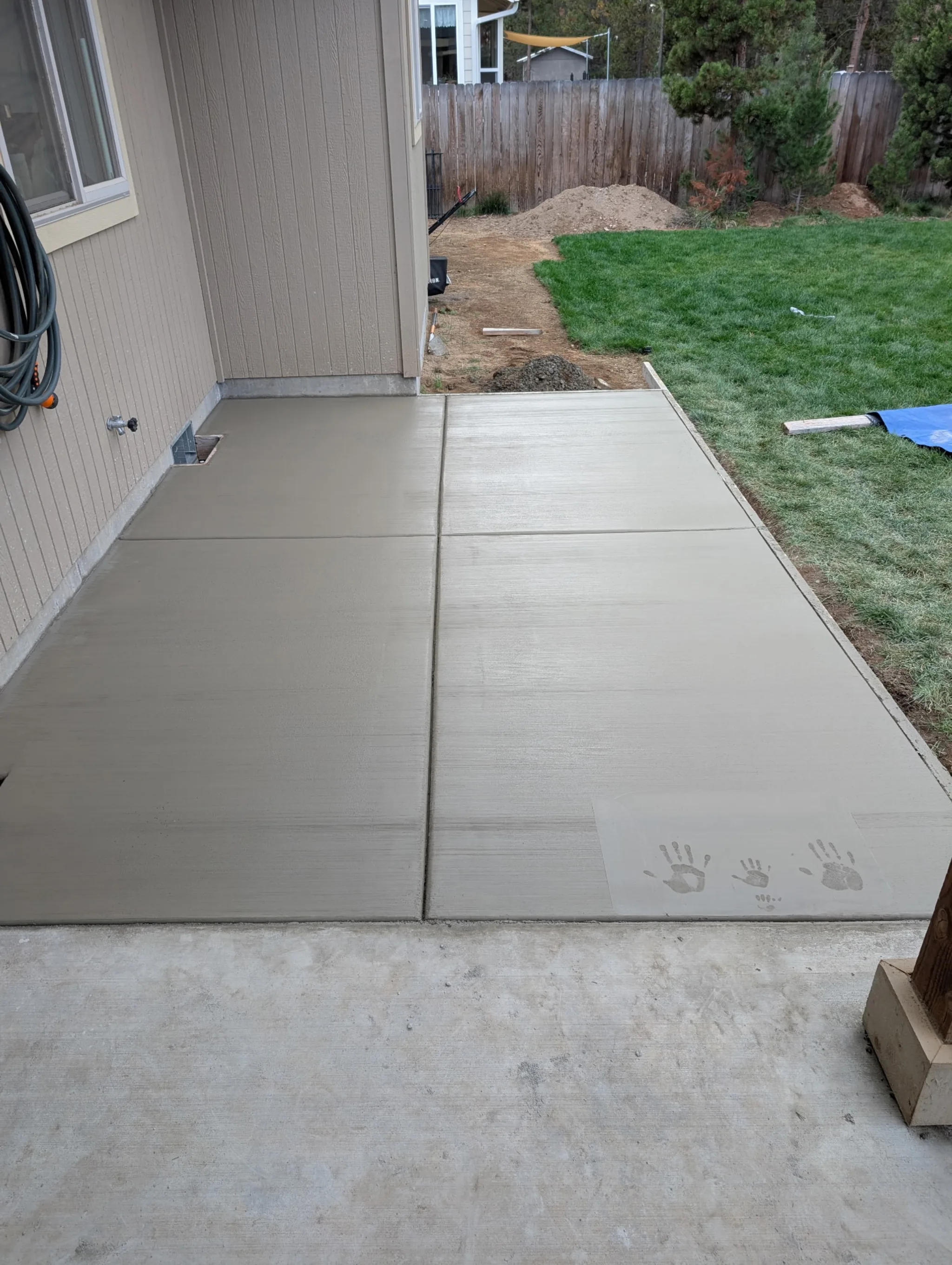 Finished backyard pad with kid handprints in the cure
